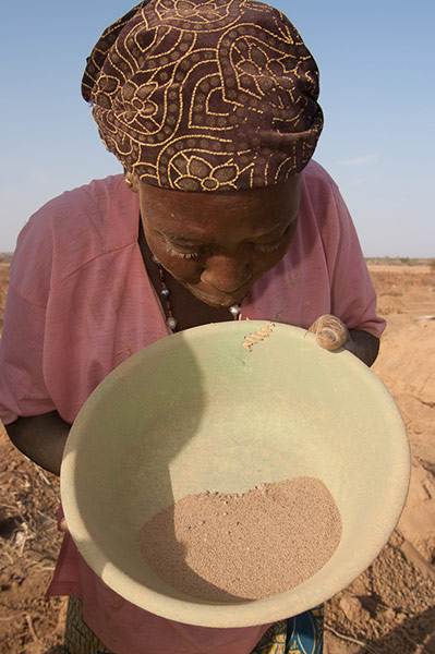 Women sweep up the dust from the process and pan it for any gold that might have been missed